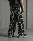 Person wearing Spectral Skull Wide Leg Trousers with bold skull graphics against a gray industrial backdrop.