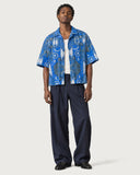 Cathedral Boxy-Fit Cuban Shirt worn open over a white tank with navy pleated trousers
