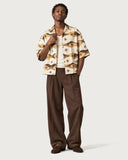 Compass Boxy-Fit Cuban Shirt worn open over a cream tank with brown pleated trousers