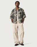 Renaissance Boxy-Fit Cuban Shirt worn open over an off-white tank with cream pleated trousers